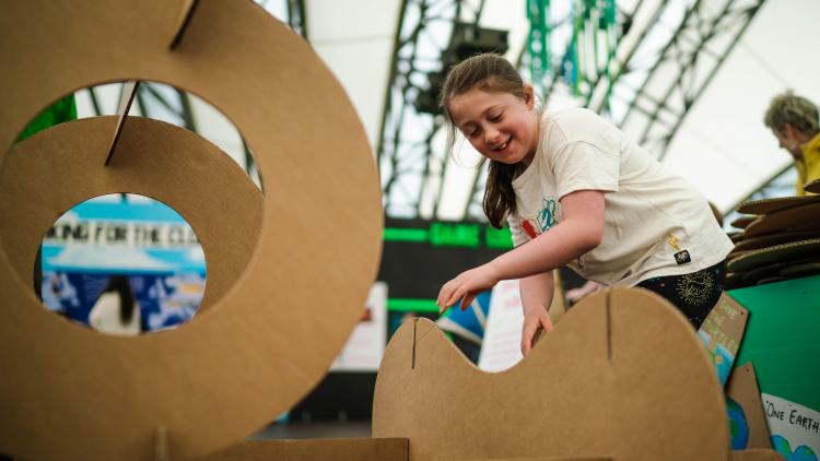 Girl building a sculpture out of large cardboard shapes that slot together